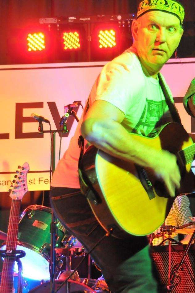 STEViE ZiPP playing the guitar on stage whilst looking back over his shoulder