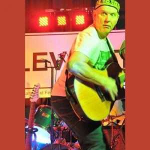 STEViE ZiPP playing a guitar whilst looking back over his shoulder