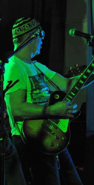 ZiPP playing a guitar solo on stage whilst wearing a sparkly fezz hat