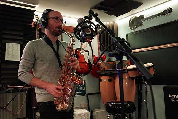 Tom O Martin playing a saxophone in a recording studio