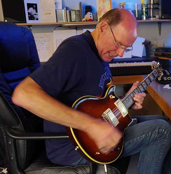Ian Housley sitting in the recording studio playing a Les Paul guitar