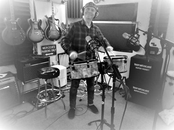 STEViE ZiPP wearing headphones in the studio whilst playing a drum