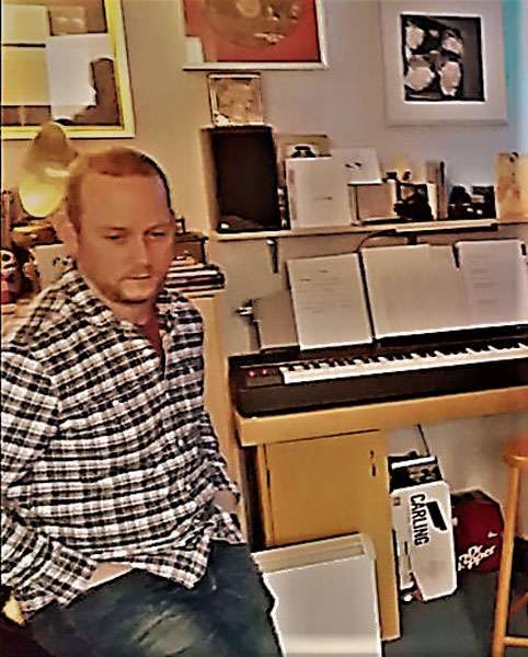 Jacob Allinson sat beside an organ in the recording studio
