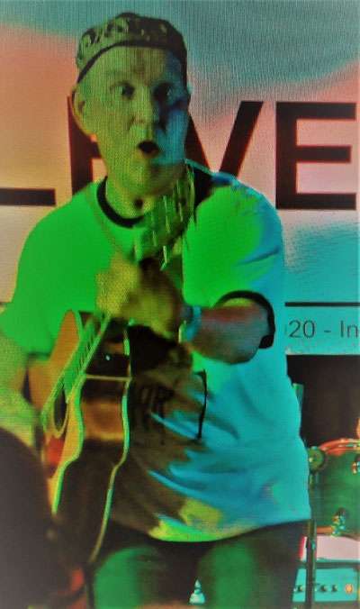 STEViE ZiPP playing guitar and singing into a microphone onstage