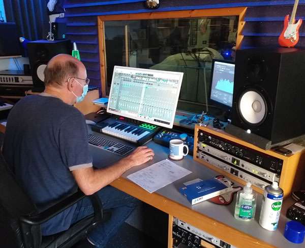 Ian Housley wearing a COVID face mask whilst mastering tracks on a computer in the studio